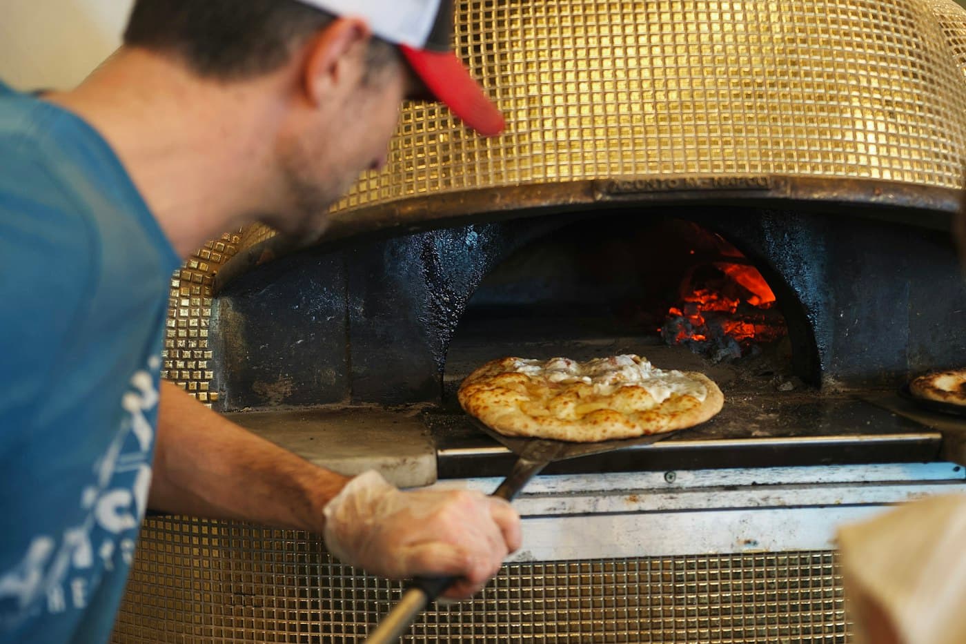 Pizzaiolo schuift een pizza in de houtoven